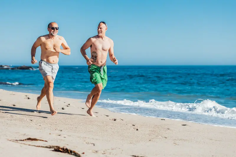 Two older men running on a beach